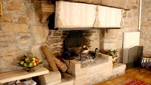 Una chimenea de piedra con fuego, un frutero y una alfombra roja en el suelo.
