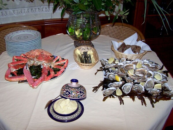 A table set with seafood dishes, a bowl of butter, and a decorative vase. - Manoir de Bodevran (Noyal-Muzillac)