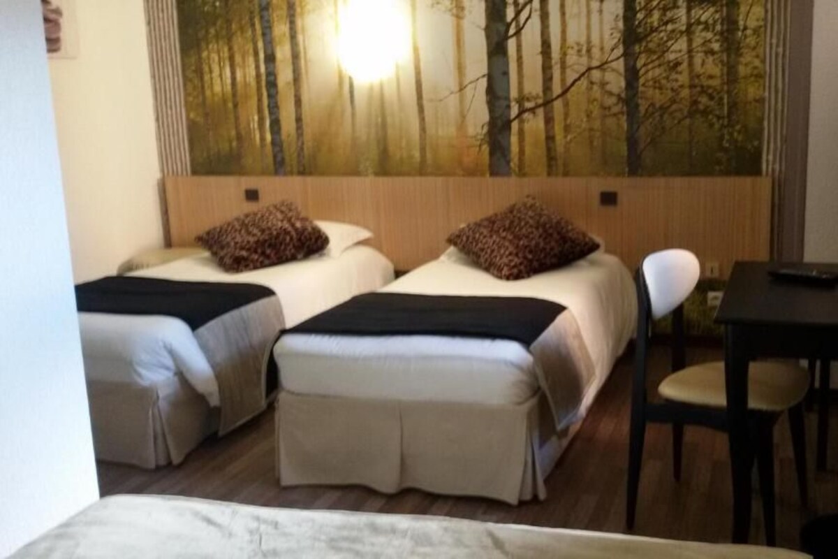 A hotel room with two beds, a desk, and a chair.