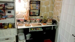 A kitchen with a stone wall, a bread rack, and various food items. - Hotel Le Merle Blanc (Digoin)