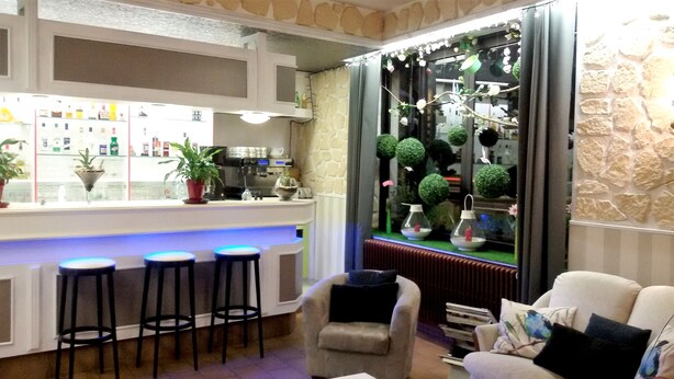 A bar area with stools, a counter, and a decorative plant display. - Hotel Le Merle Blanc (Digoin)