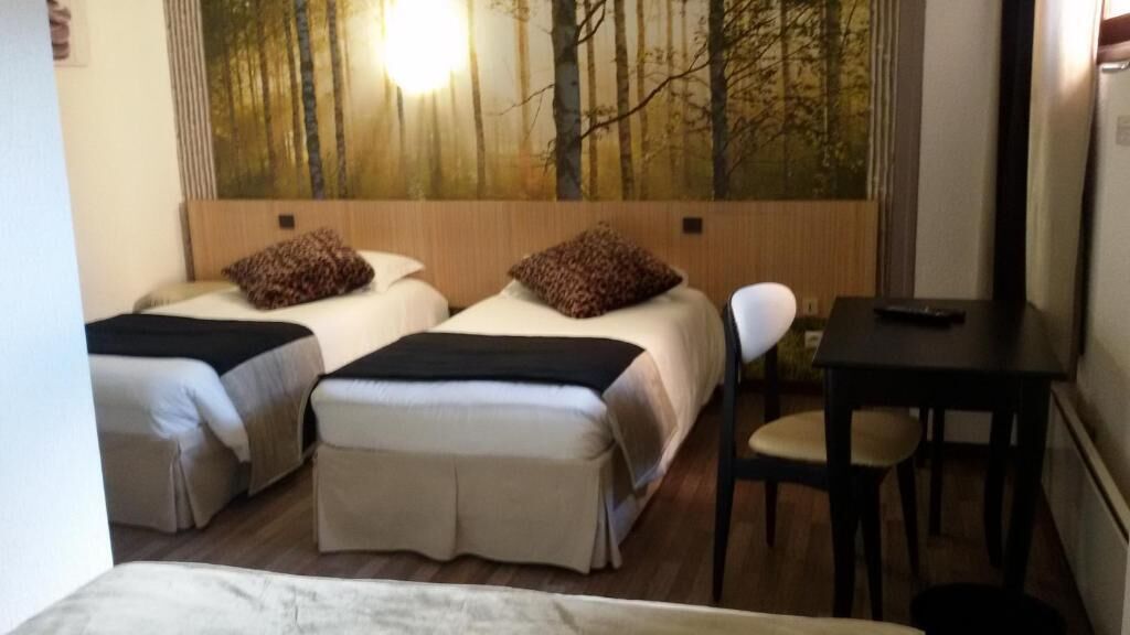A hotel room with two beds, a desk, and a chair.