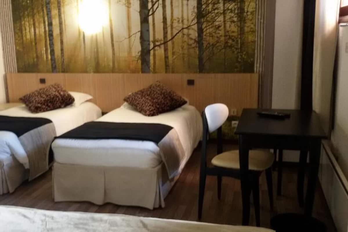 A hotel room with two beds, a desk, and a chair.