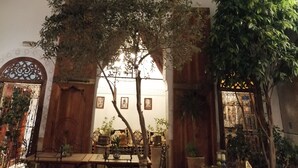 A courtyard with arched windows, a wooden door, and potted plants. - Riad Attarine (Fes)