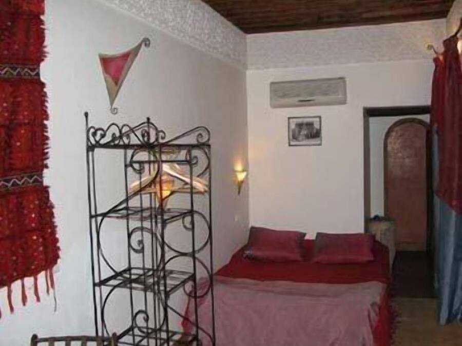 A room with a bed, a wall-mounted shelf, and a door.