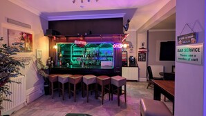 A bar area with a neon sign, bar stools, and a counter with various bottles. - Cecil Court Hotel (Bournemouth)