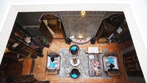 An overhead view of a hotel lobby with a central seating area, a patterned ceiling, and a decorative fountain. - The Repose (Salé)