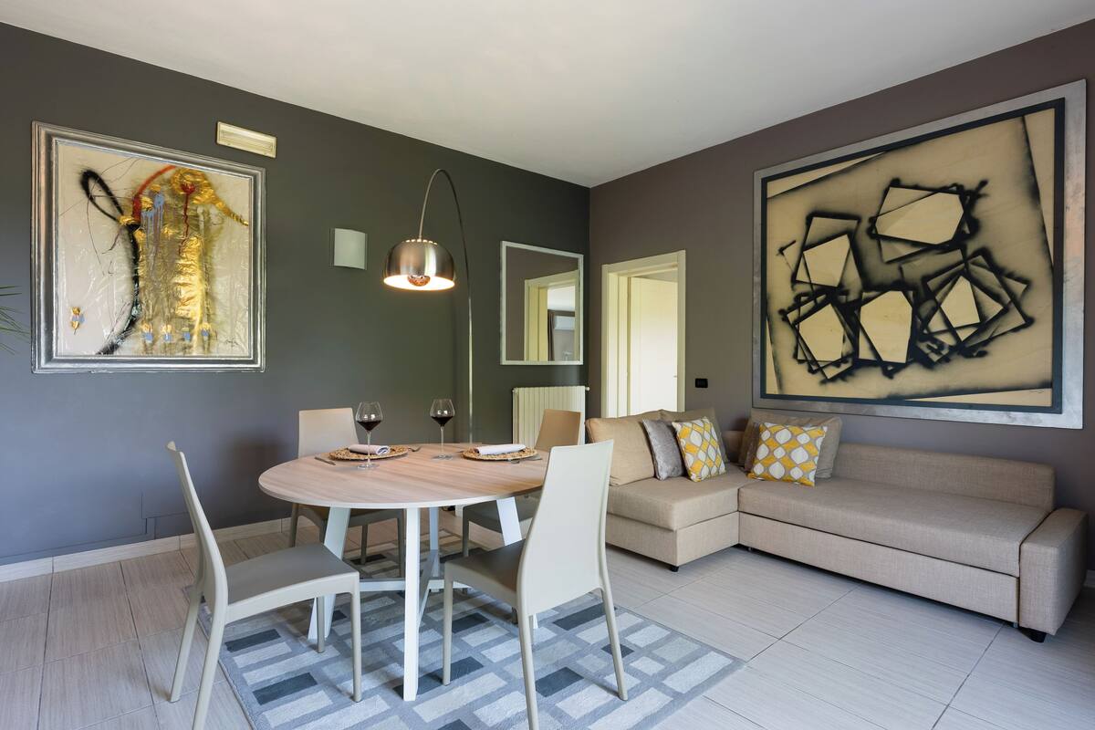 A modern living room with a round dining table, a sofa, and abstract art on the walls.