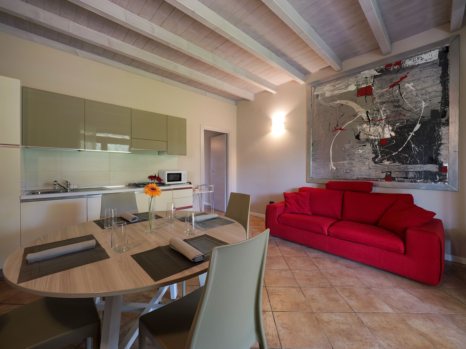 Una cocina moderna con comedor, un sofá rojo y un cuadro abstracto grande.