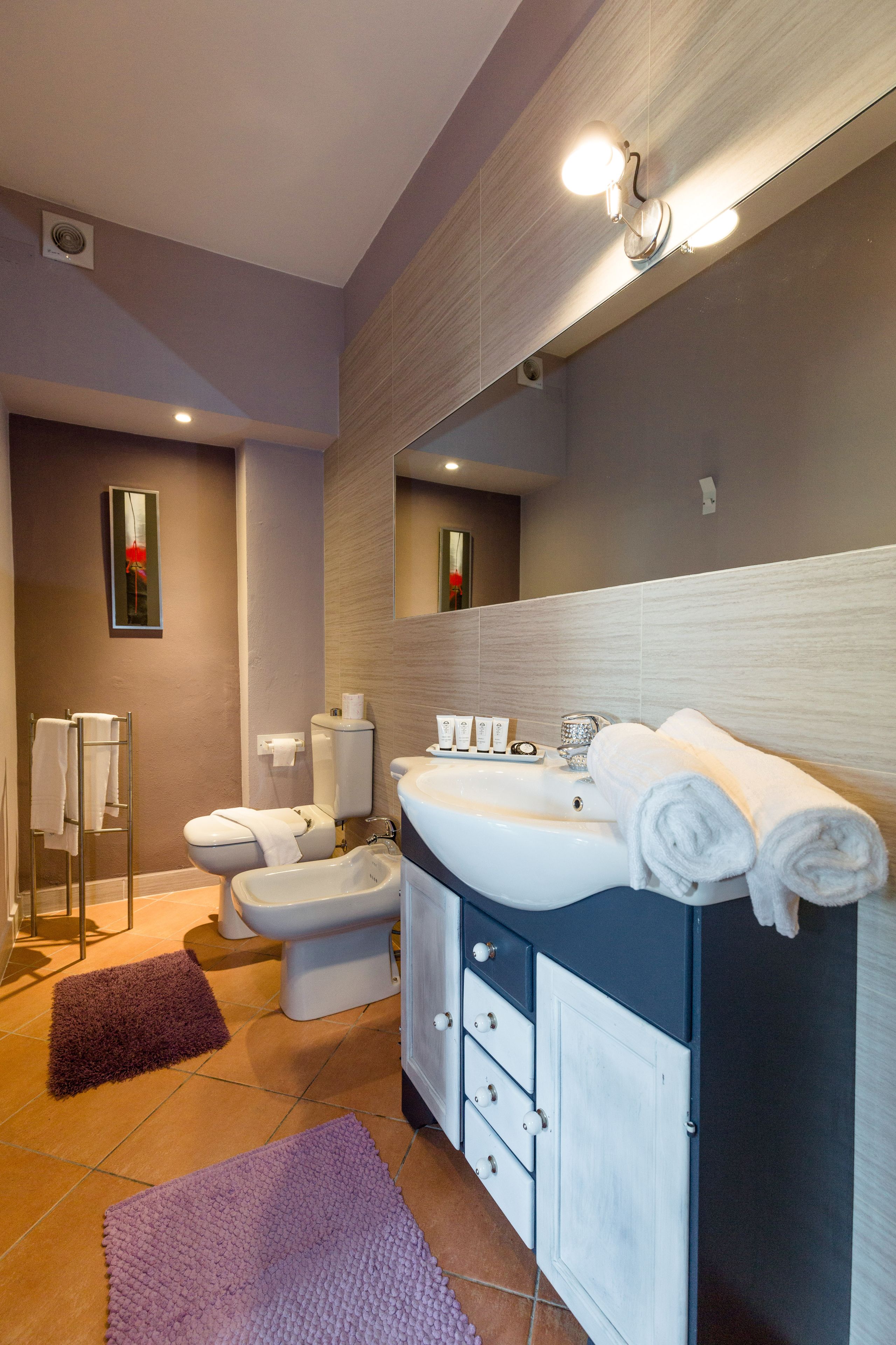 Un baño moderno con tocador, inodoro, bidé y un espejo grande.