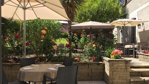 An outdoor patio with a table and chairs, surrounded by a brick wall and potted plants.