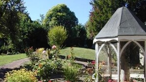 A garden with a gazebo, surrounded by various plants and flowers.