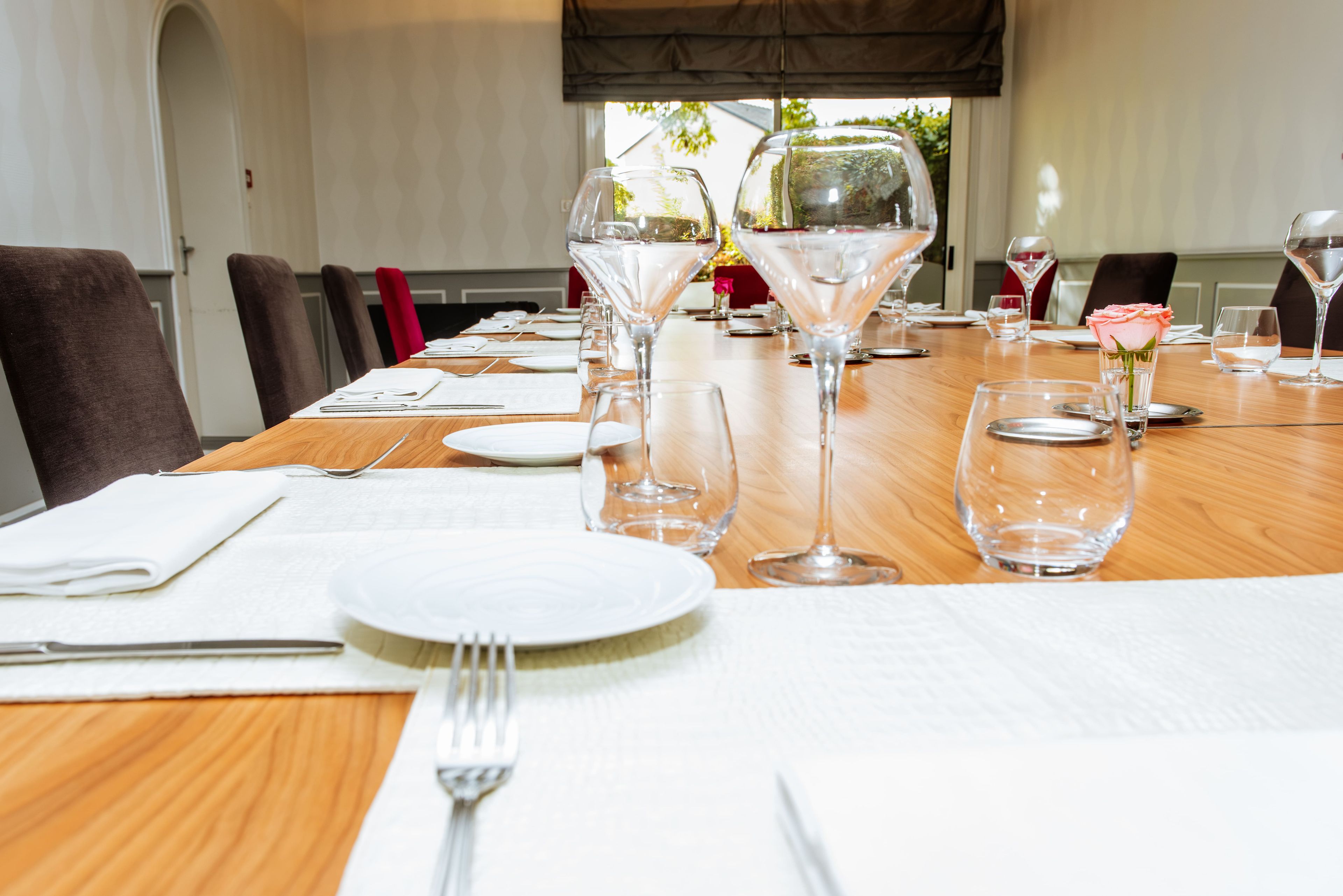 Mesa de jantar posta com diversos copos de vinho, pratos e talheres, sugerindo uma refeição formal.