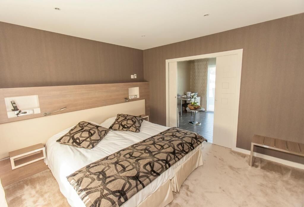 A bedroom with a large bed, bedside tables, a mirror, and a view of a bathroom.