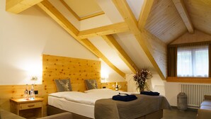 Une chambre avec un plafond en bois, un lit avec une tête de lit, une table de chevet, un vase avec des fleurs et une fenêtre avec des rideaux.