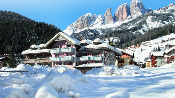Un bâtiment enneigé doté d’un balcon, entouré de neige et avec des montagnes en arrière-plan.