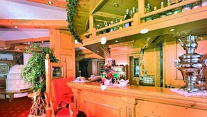 Un espace bar avec des meubles en bois, une moquette rouge et une variété de bouteilles et de verres exposés sur des étagères.