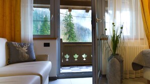 Une chambre avec un lit, une fenêtre donnant sur des arbres et une plante sur une table.
