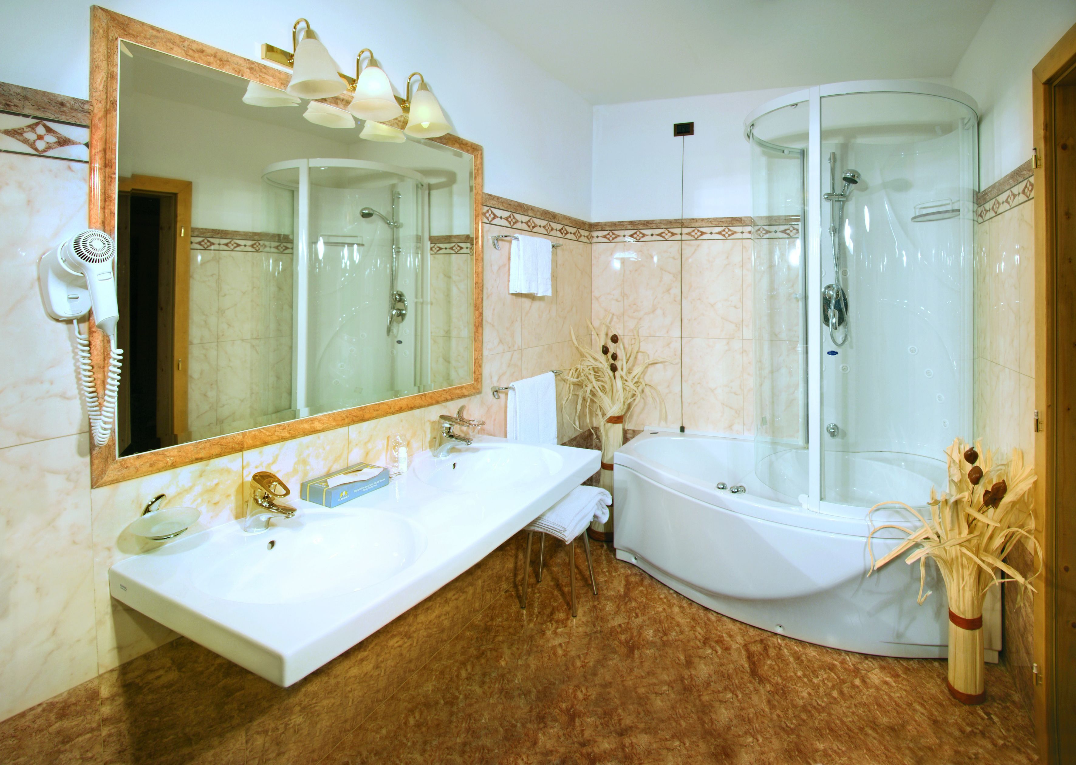 Ein Badezimmer mit großem Spiegel, weißem Waschbecken, Badewanne und einer Duschkabine.