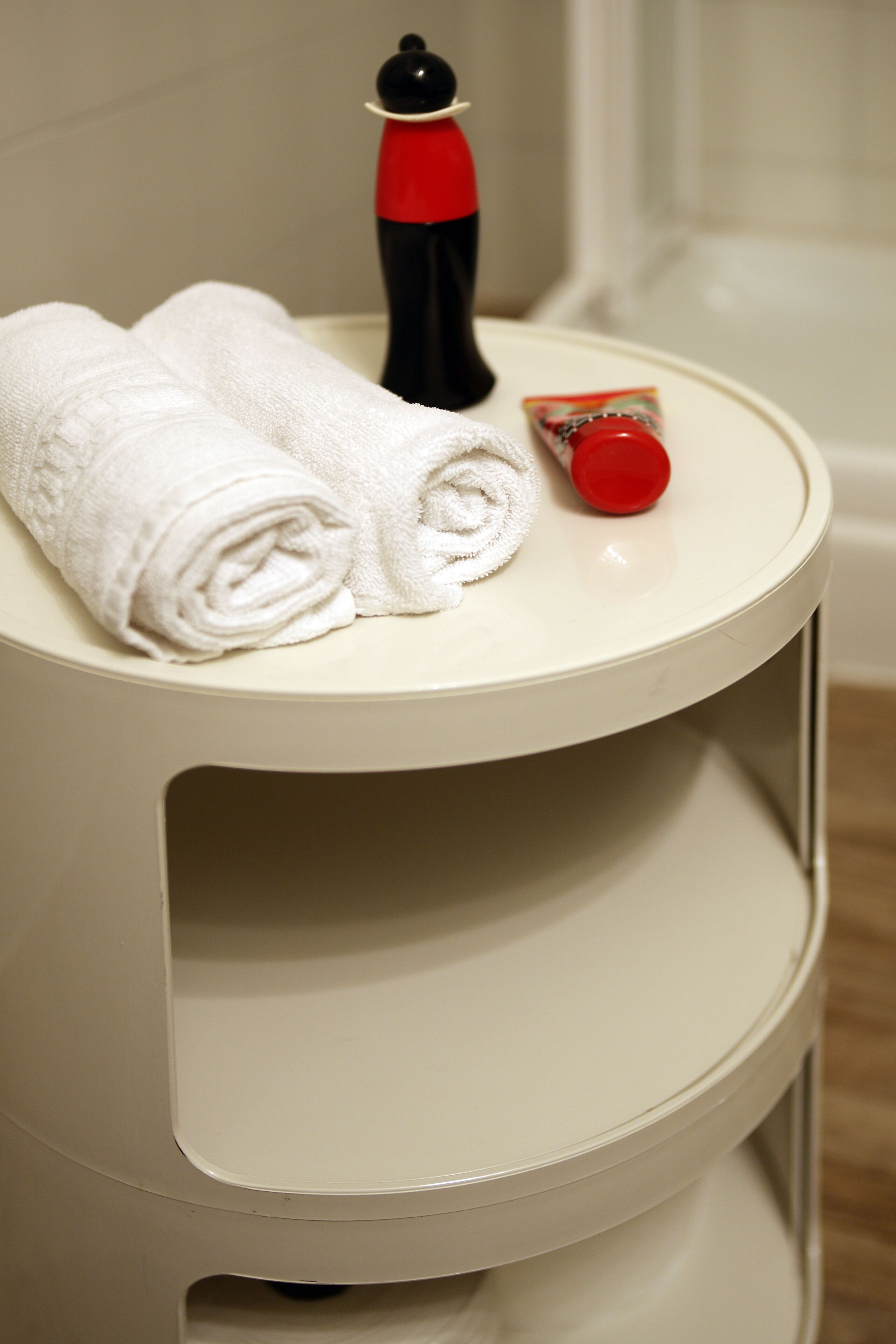 A white bathroom vanity with a towel and a red bottle on top.