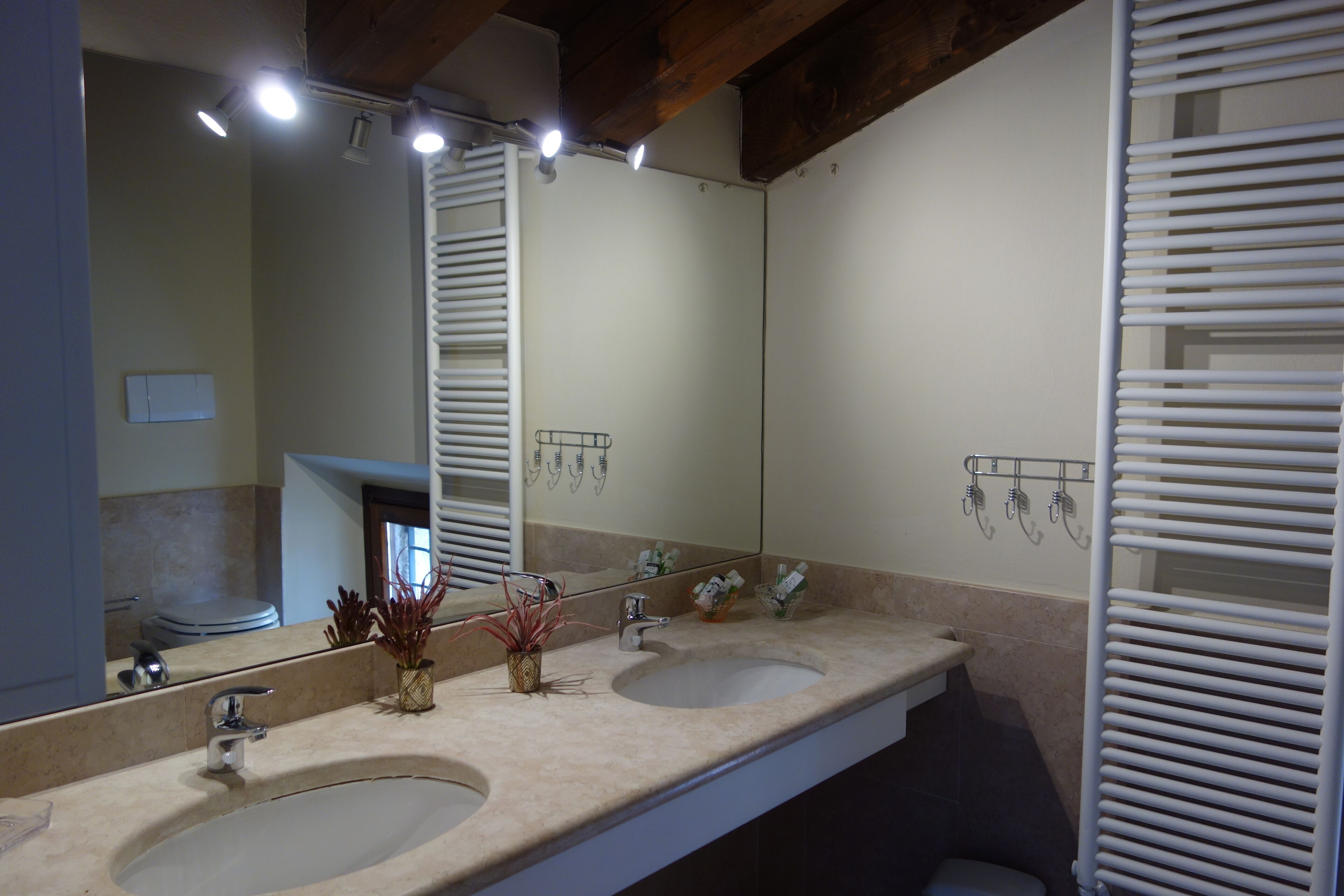 Un baño con dos lavamanos, un espejo grande y barras para toallas.