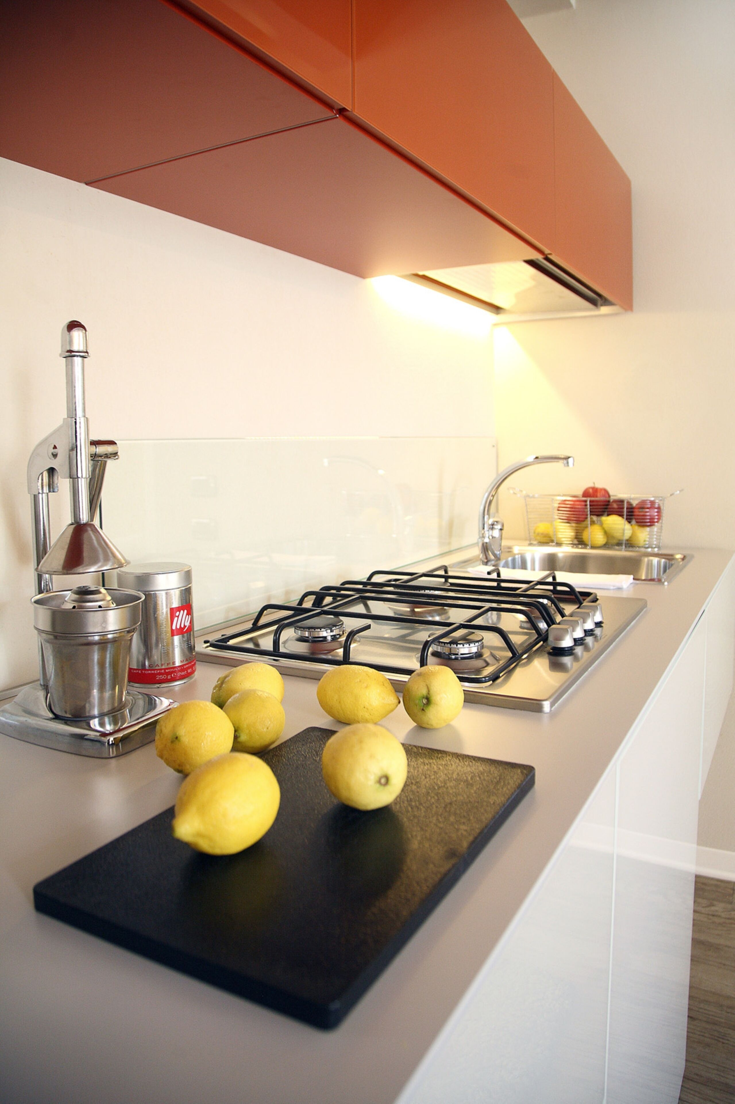 Una cocina con estufa a gas, un fregadero y una tabla de cortar con limones.