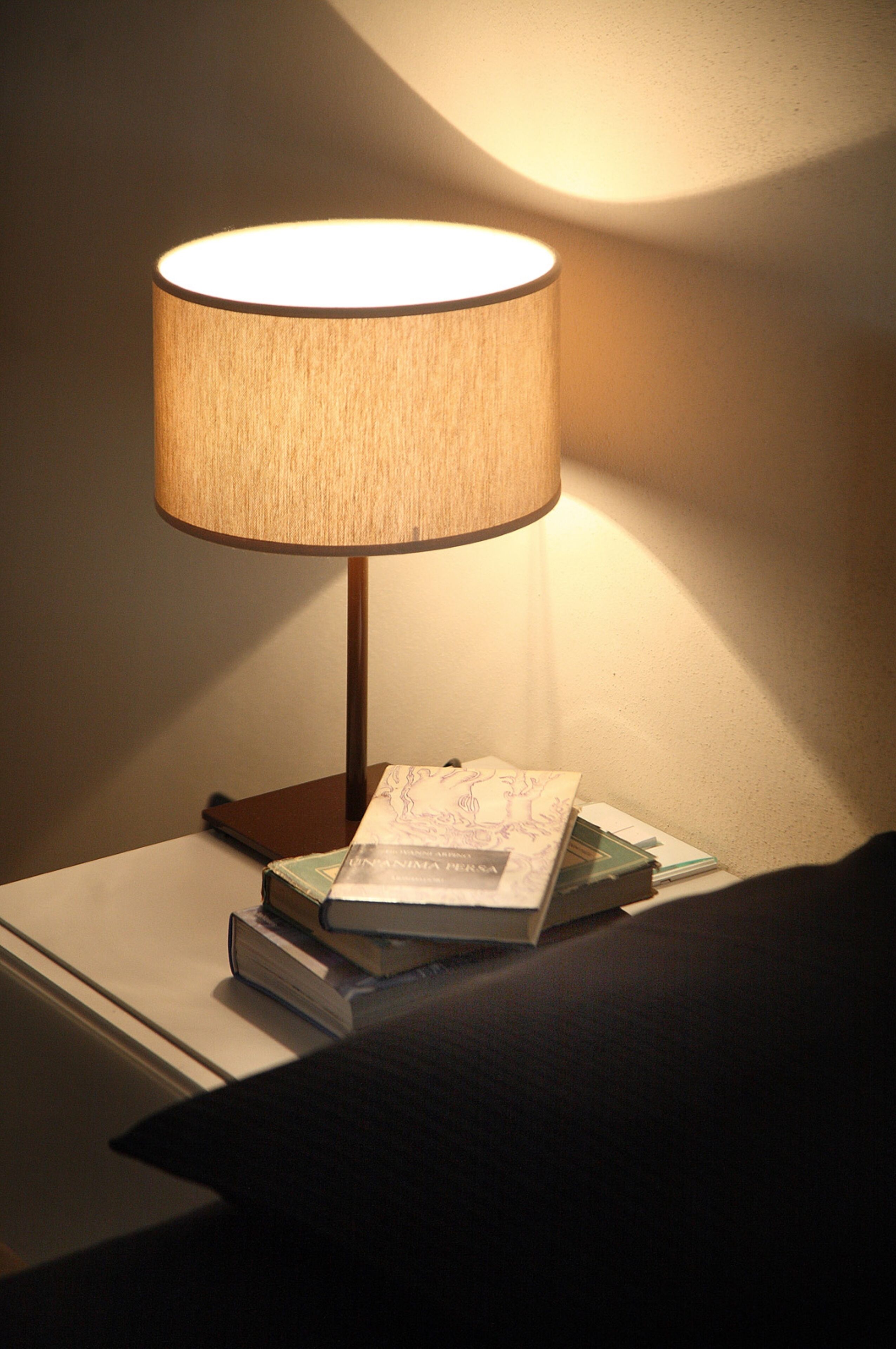 Ein Nachttisch mit Lampe, einem Buch und Papierstapel.