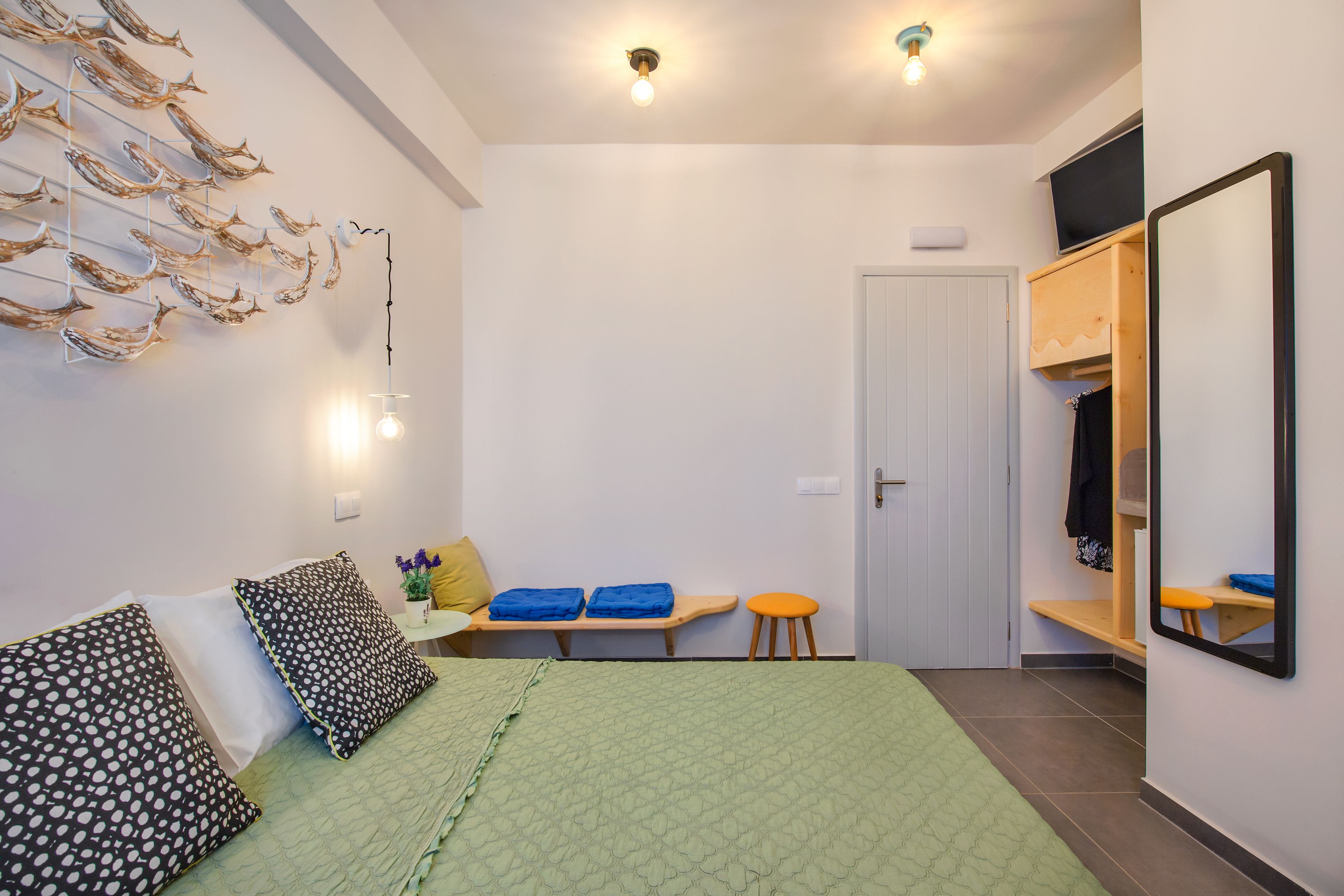 A bedroom with a bed, a bench, a stool, a wardrobe, and a mirror.