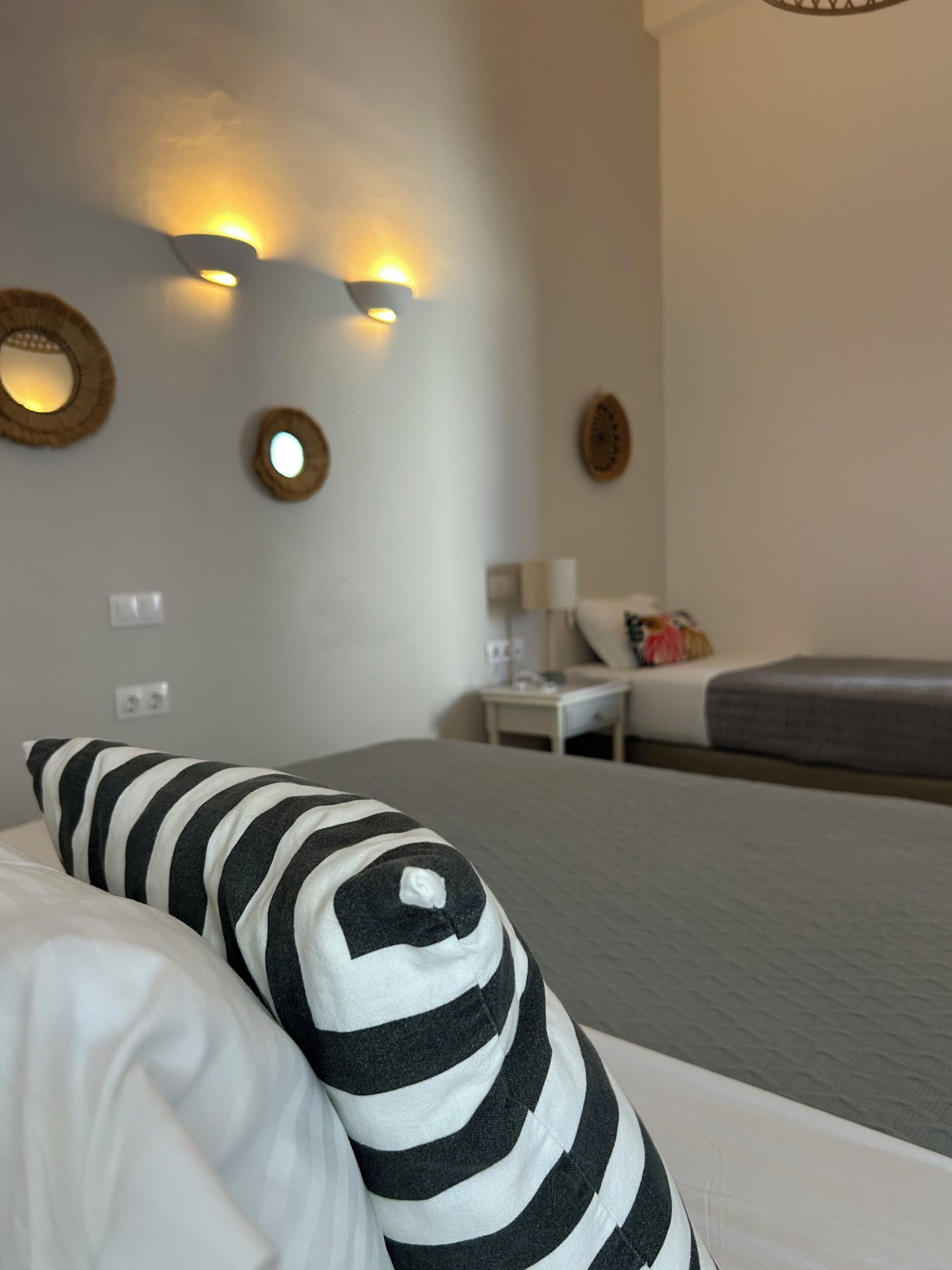 A hotel room with a bed, a nightstand, a lamp, and wall-mounted light fixtures.