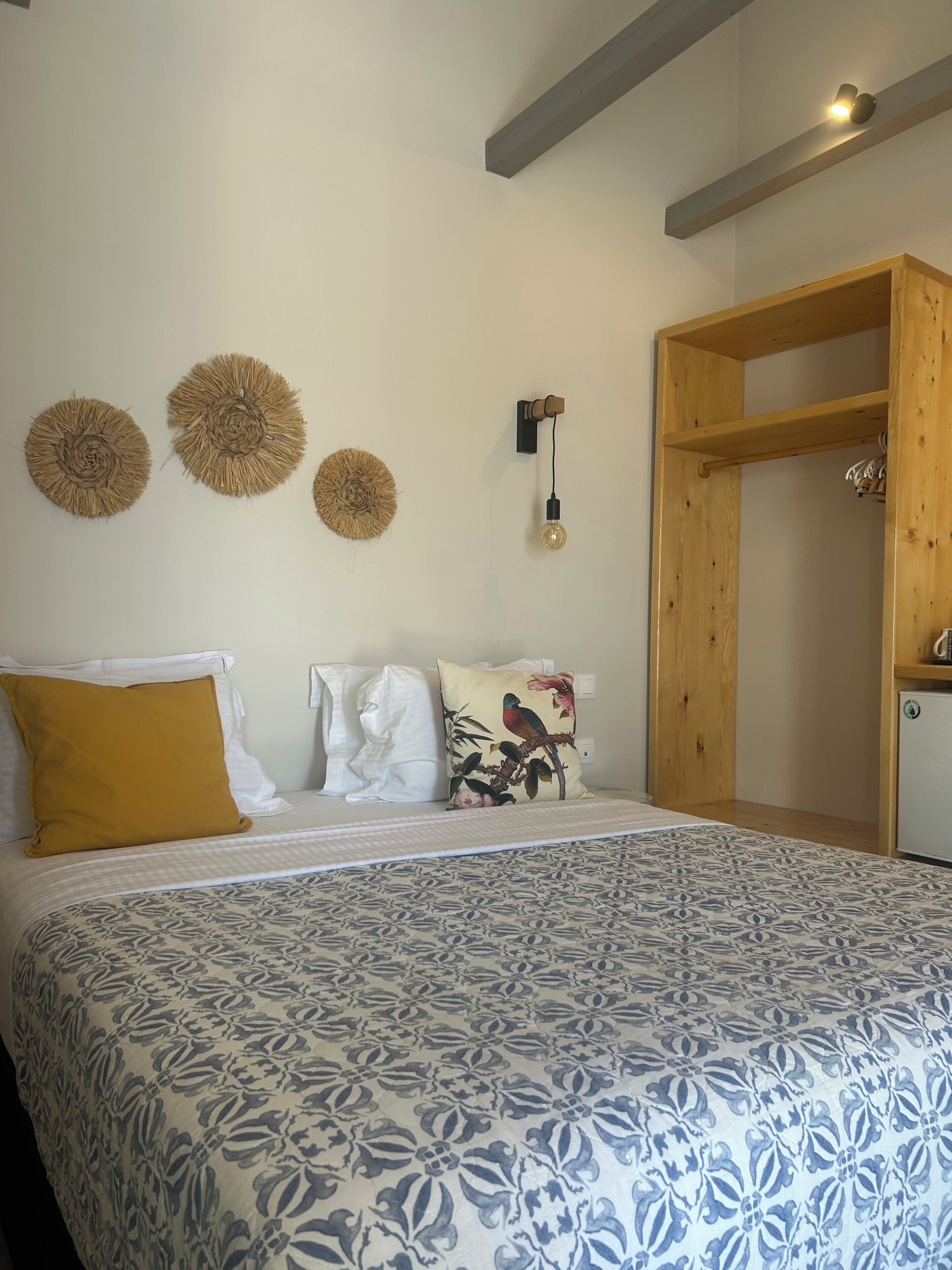 A bed with patterned bedding, a wooden wardrobe, and three wall-mounted decorative items.