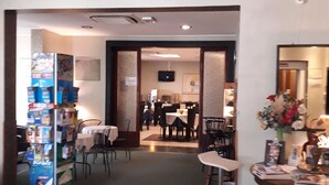 A hotel lobby with a reception desk, a dining area with tables and chairs, and a vending machine. - Hotel Niagara Rimini (Rimini)