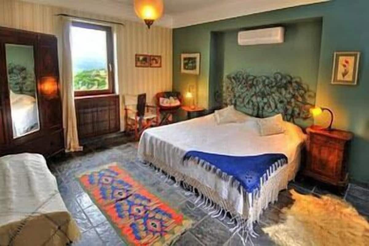 Quarto com cama, janela, porta e tapete.