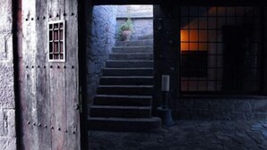 Una escala de pedra rústica que porta a una porta de fusta amb una finestra reixada.