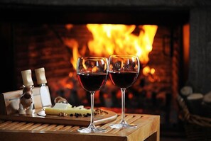 Two glasses of red wine on a wooden tray with cheese and nuts, in front of a fireplace. - Assos Alarga (Ayvacik)