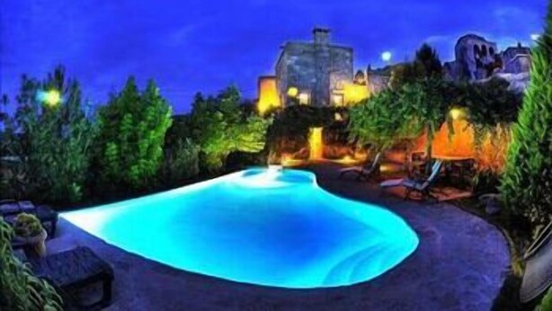 Vista nocturna d'una piscina amb un edifici de pedra al fons.