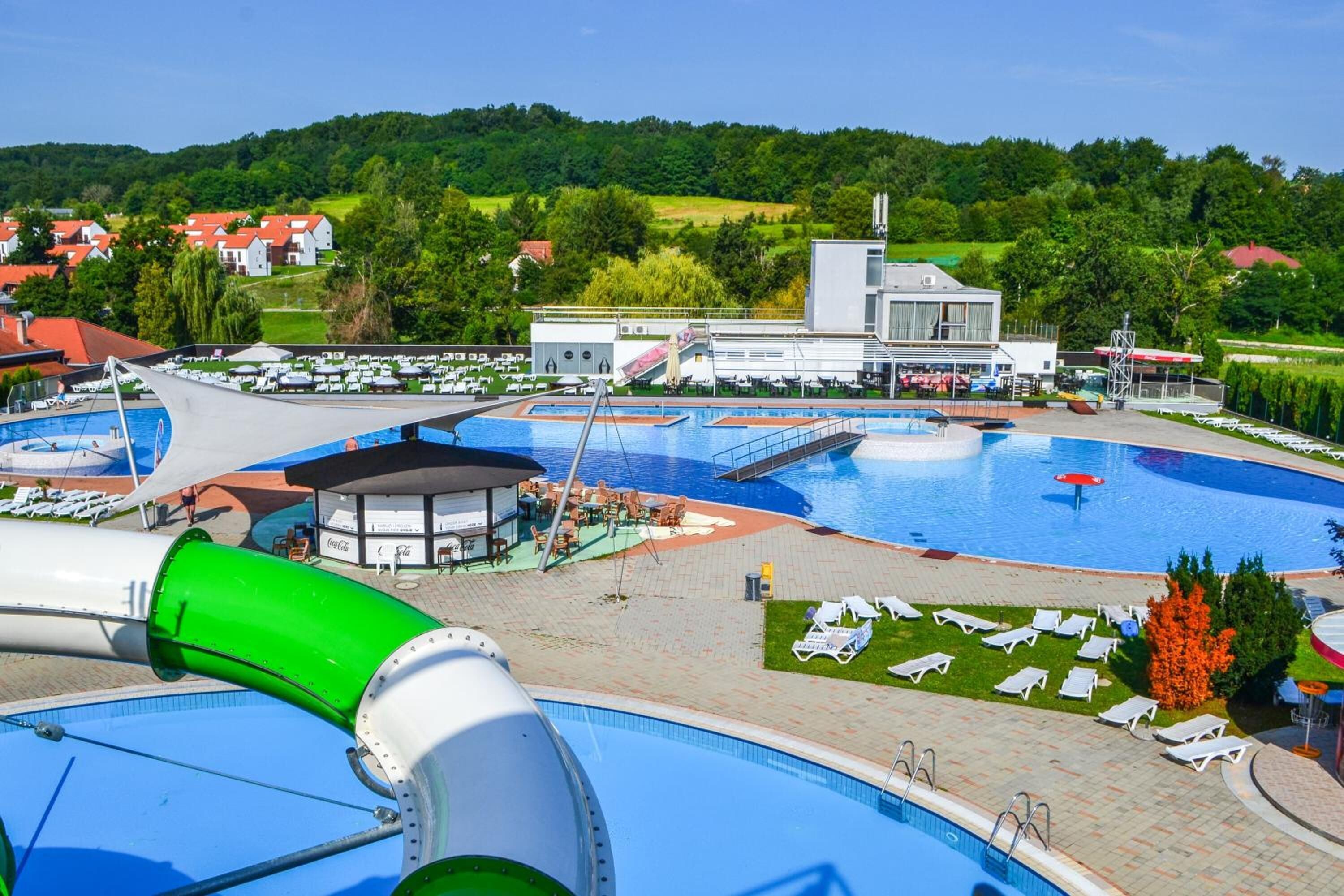 Un área de piscina con varias piscinas, sillas de descanso y un edificio de diseño moderno.