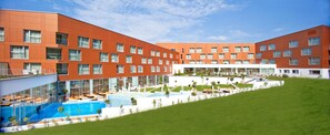 A modern hotel with multiple floors, a swimming pool, and a landscaped garden area.