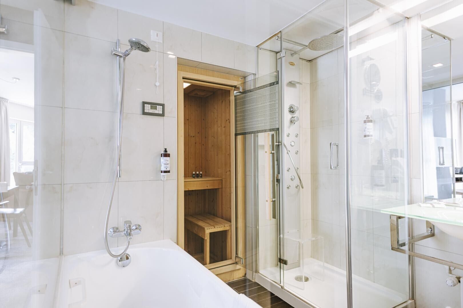 A modern bathroom with a glass-enclosed shower, a wooden sauna, and a white bathtub.