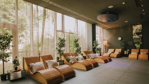 Un cuarto de spa con camastros de madera, ventanas amplias y plantas en macetas.