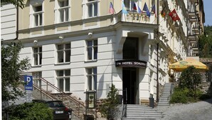 Ein historisches Hotel mit einer klassischen Fassade, mehreren Flaggen und einem Schild, das es als Wellnesshotel kennzeichnet.