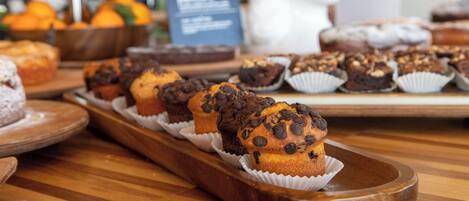 A wooden tray with muffins and a bowl of oranges.