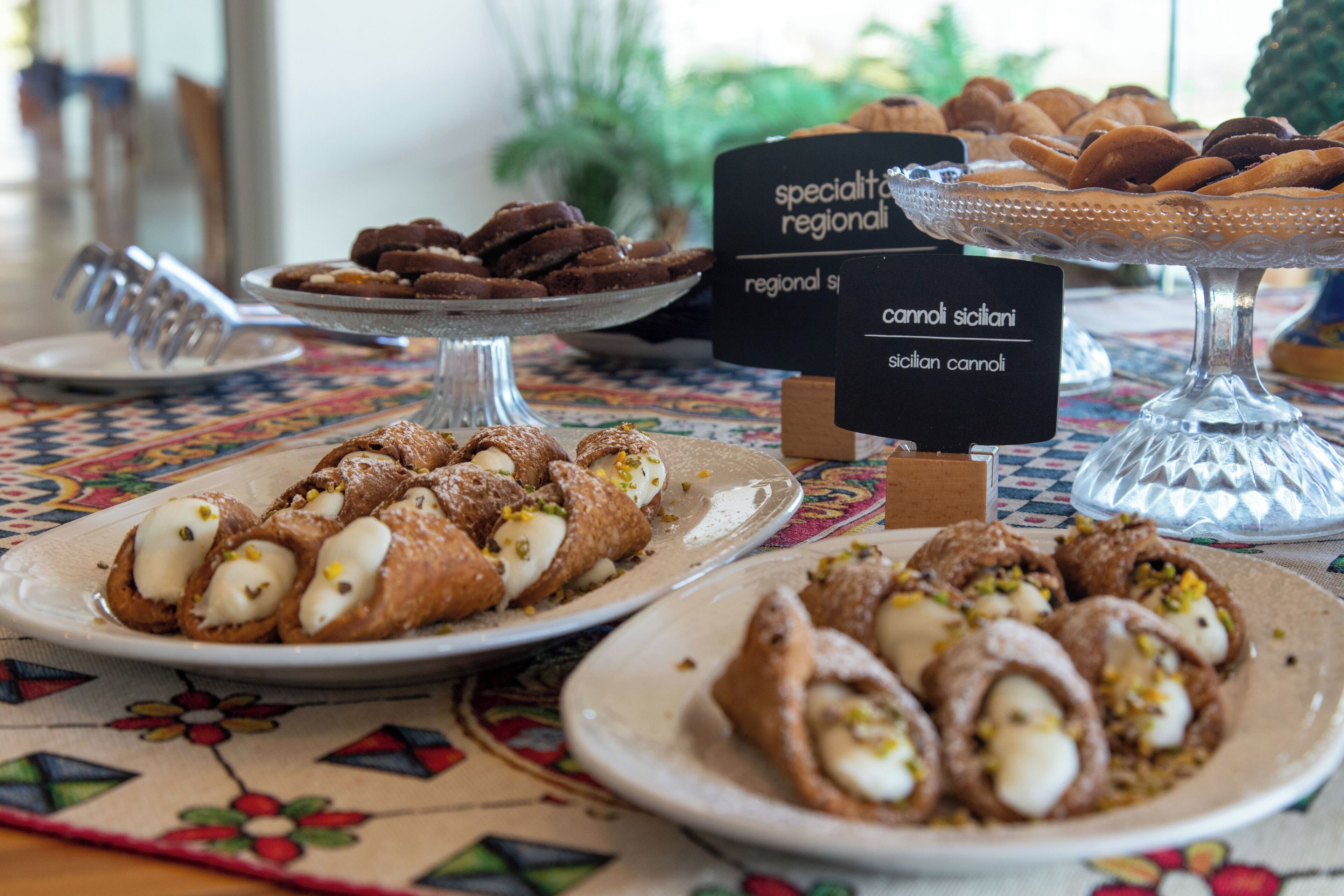 A buffet table with various regional specialties, including cannoli and other desserts.