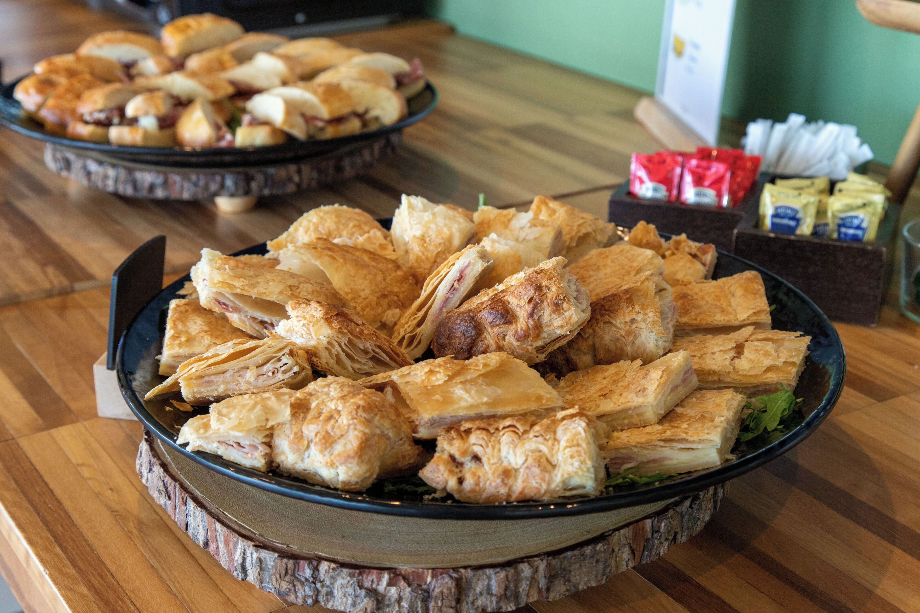 A wooden table with a large platter of pastries and a smaller dish in the background.