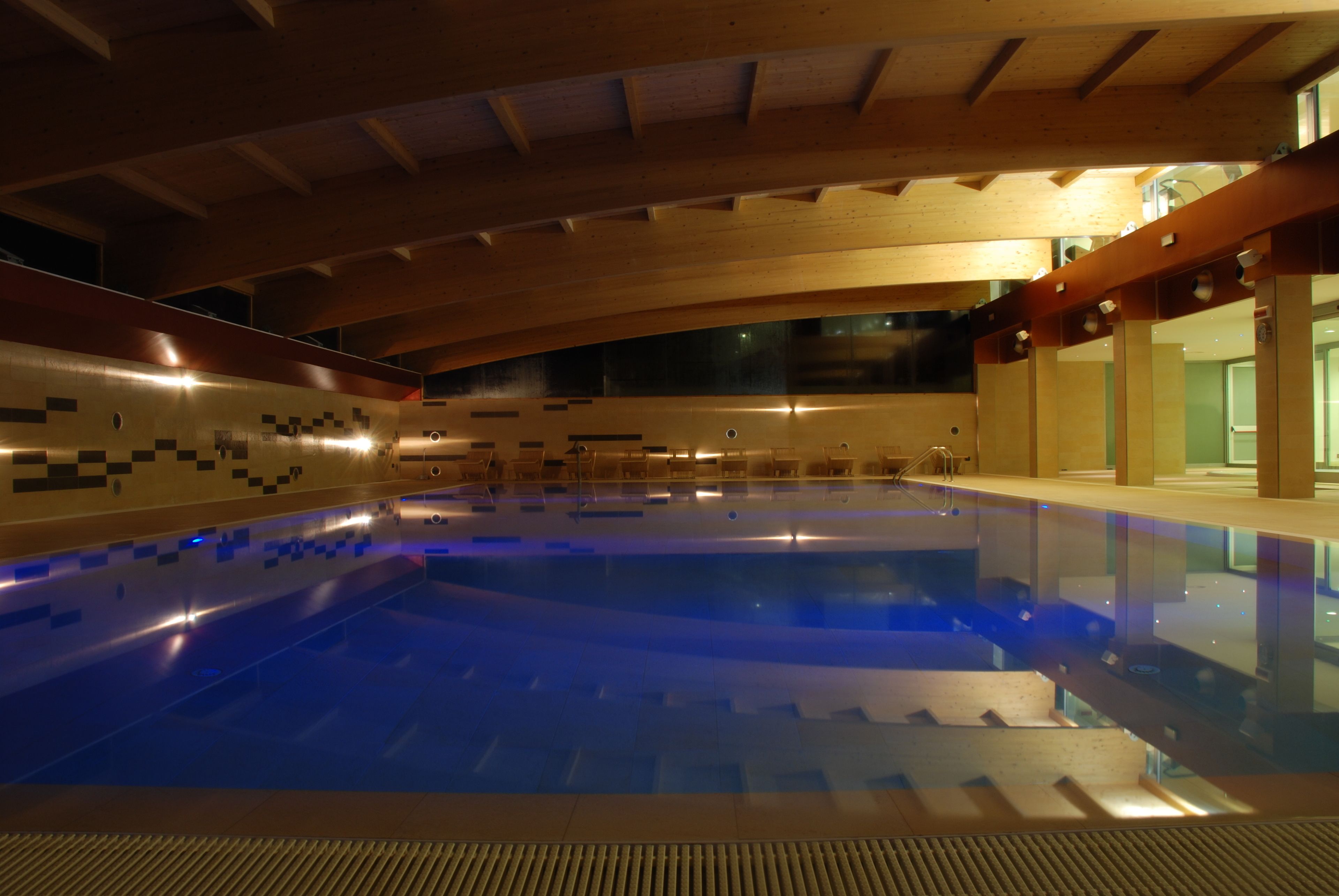 An indoor swimming pool with a wooden ceiling and tiled walls.