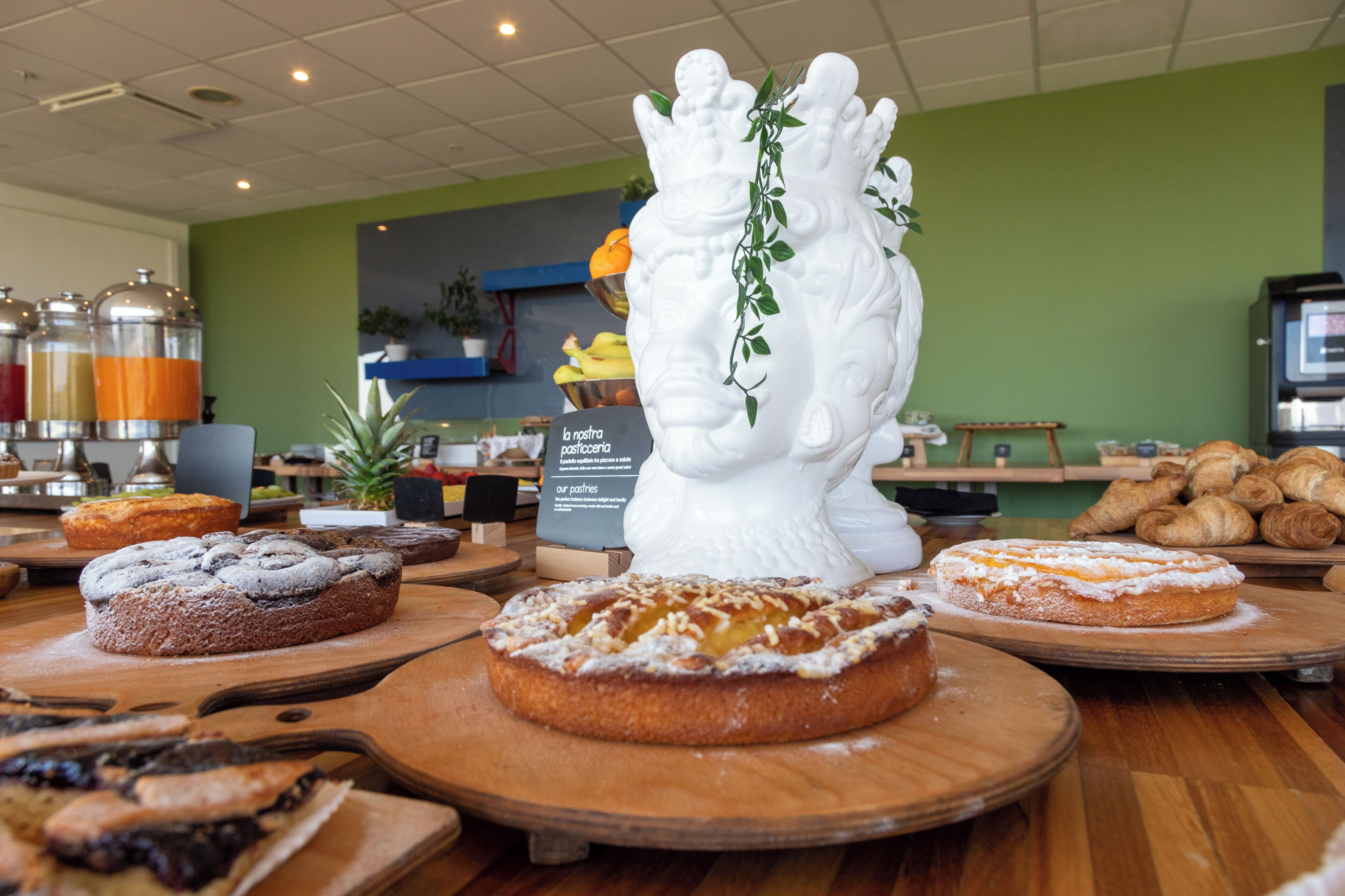 A bakery display with various pastries and a decorative white ceramic piece.