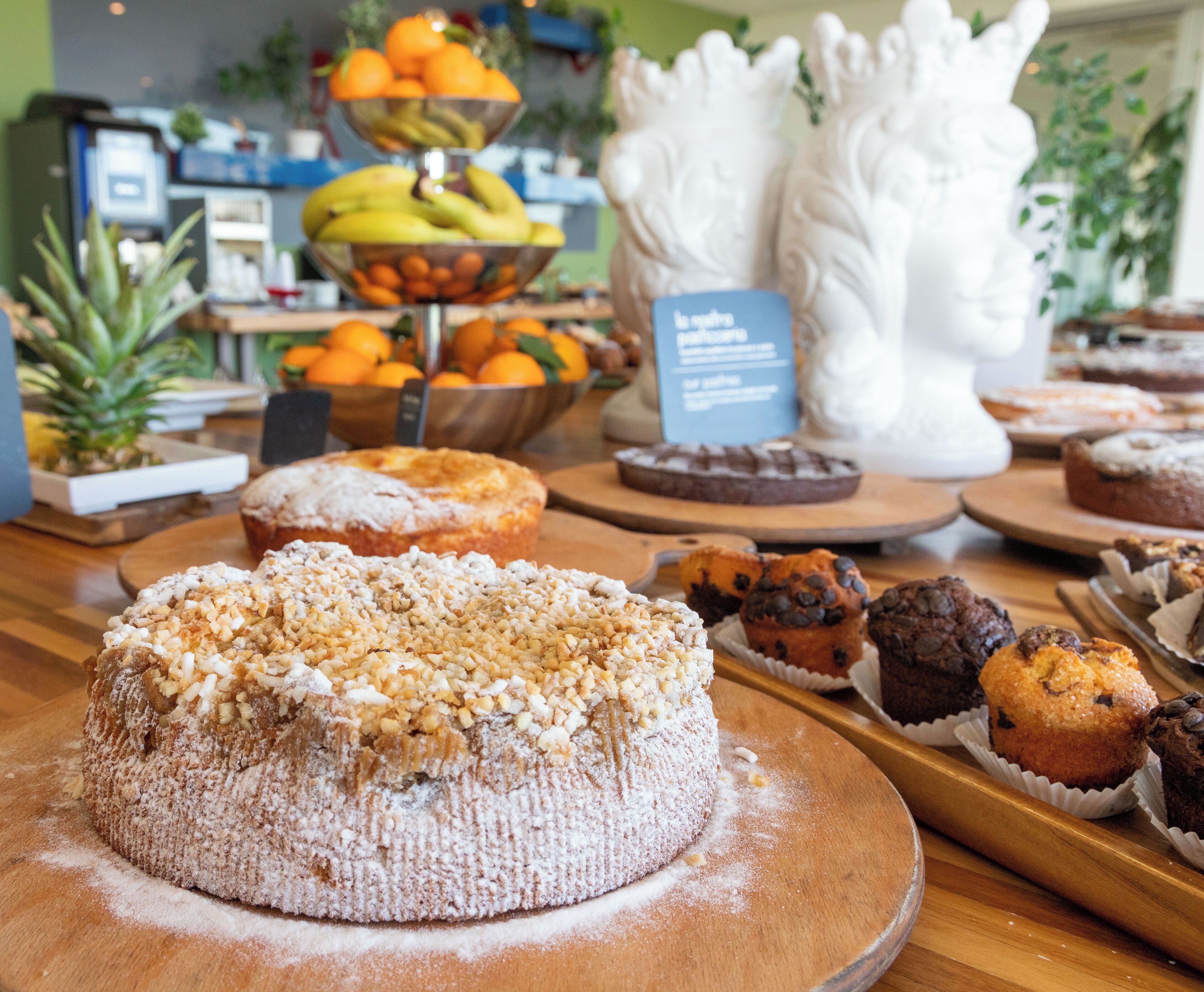 A variety of baked goods on display, including a cake with a powdered topping and several muffins.