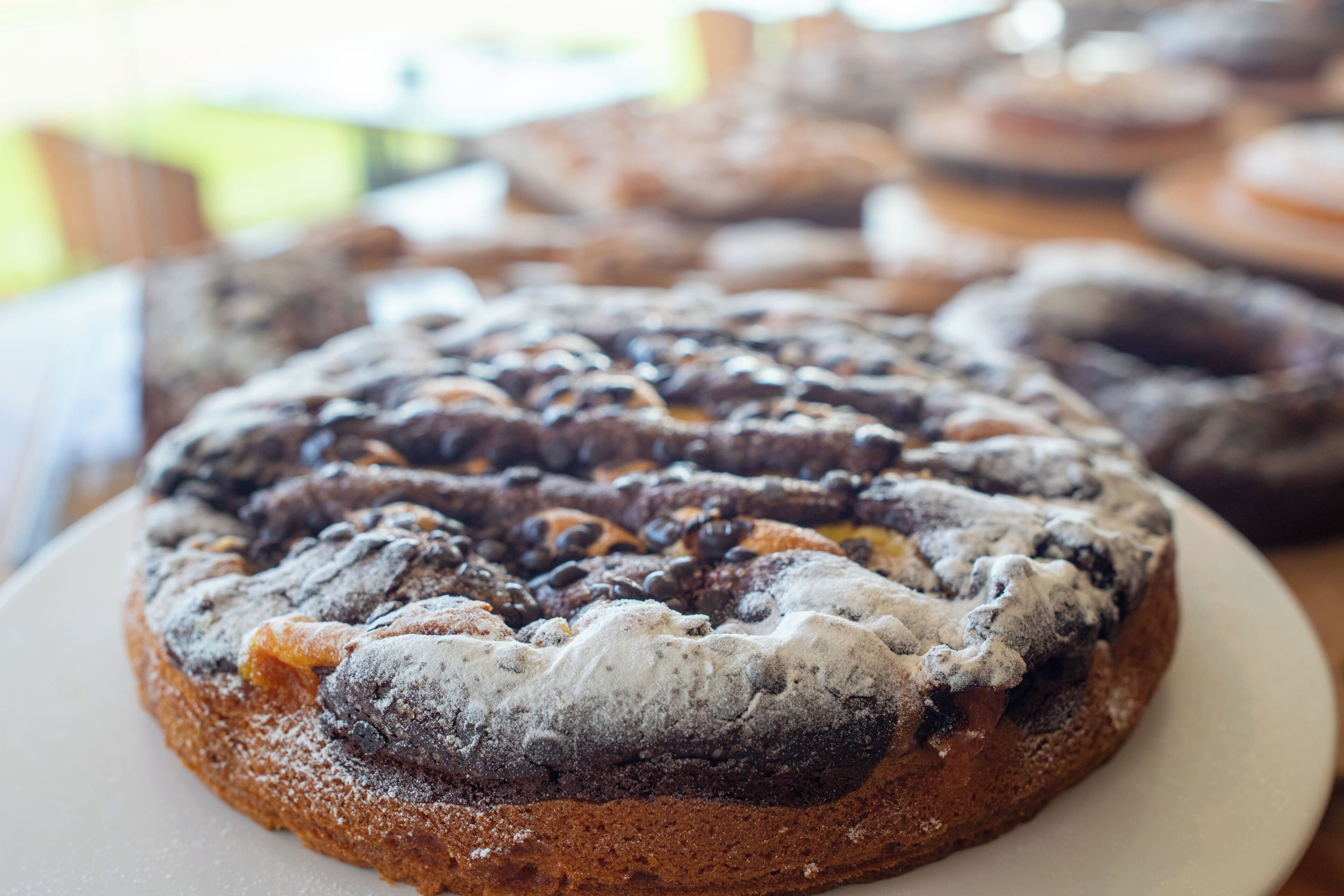 Un pastel redondo con chispas de chocolate y una capa de azúcar glas sobre un plato.