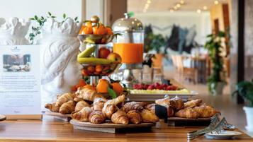 Un ricco buffet per la colazione con dolci, frutta e un distributore di succhi.