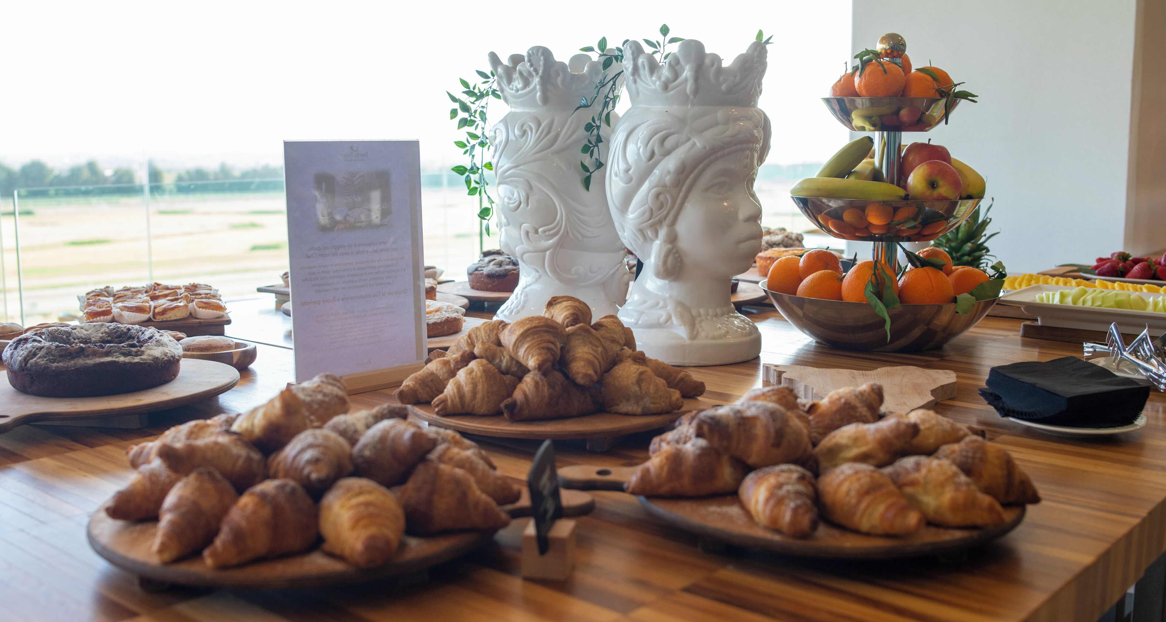 A buffet table with croissants, pastries, and a fruit display.