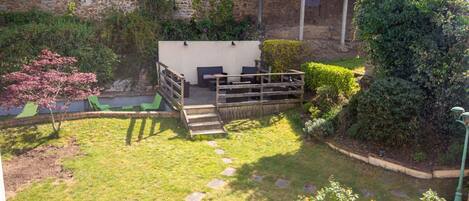 A courtyard with a seating area, stone wall, and greenery.